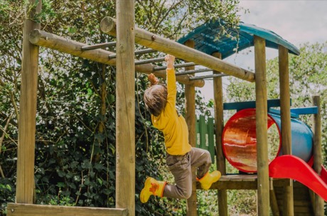 Un niño juega en el pasamanos del parque
