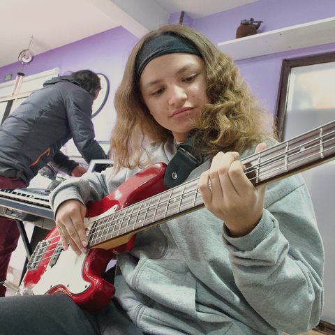 Una joven toca el bajo eléctrico en el ambiente de música